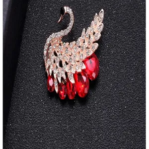 Macro view of rose gold swan brooch with red teardrop crystals and clear rhinestones