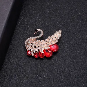 Elegant gold-toned swan brooch with brilliant red teardrop crystals