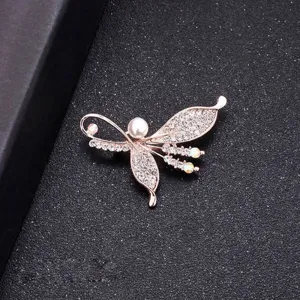 Elegant rose gold butterfly brooch with pearl and sparkling rhinestones on black background.