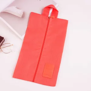 Detail view of portable travel shoe bag, waterproof coral red fabric with zipper and handle.