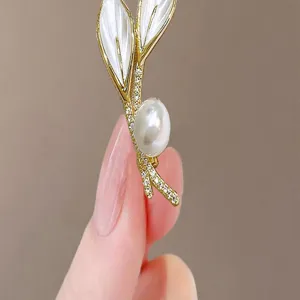 Detailed macro shot of an elegant pearl brooch with white enamel leaves and crystals