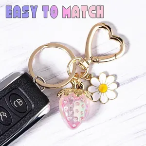 Close-up of sweet pink strawberry keychain with heart clasp and daisy charm.