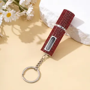Primo piano di un atomizzatore di profumo portatile con strass rossi, finestra e portachiavi.