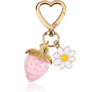 Close-up detail of sweet pink strawberry and white daisy keychain with gold heart clip