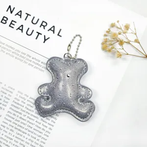 Detailed view of silver glittery leather bear keychain with metallic ball chain