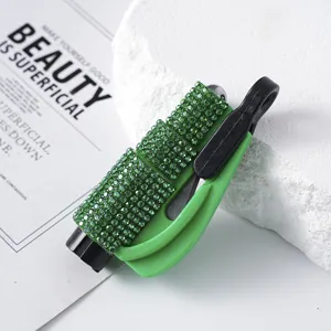 Detailed view of a green rhinestone-studded car window breaker tool on a stone base