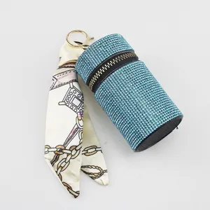 Detailed shot of a blue rhinestone lipstick holder with a chain-print silk scarf