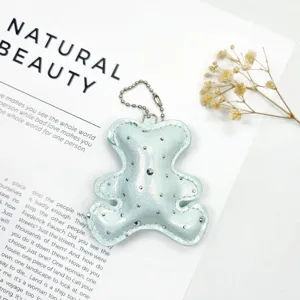 Macro detail of a sparkling mint green leather bear keychain with crystal studs.