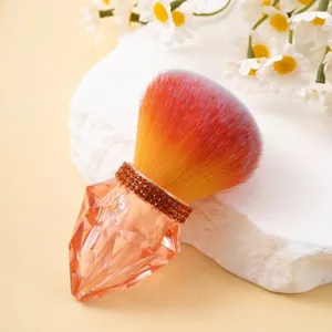 Close-up of a luxury orange nail dust brush featuring a sparkling diamond-shaped handle
