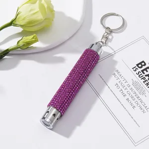 Detailed view of purple rhinestone LED flashlight keychain on elegant white background
