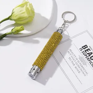 Close-up of yellow rhinestone-encrusted mini LED flashlight keychain on white card
