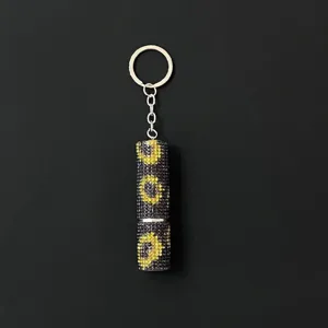 Macro detail of sparkly yellow and black rhinestone perfume atomizer keychain.