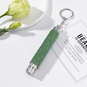 Elegant close-up view of a green rhinestone mini LED flashlight keychain on a white surface.
