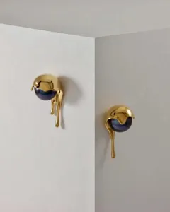 Primer plano detallado de un pendiente de oro con forma de gota y perla oscura incrustada