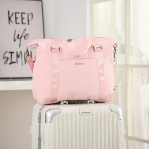 Lightweight pink large capacity travel bag with suitcase sleeve shown on white luggage.