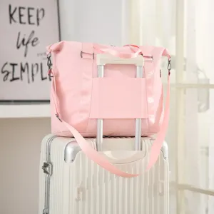 Pink travel bag with luggage sleeve detail, shown resting on a white trolley suitcase.