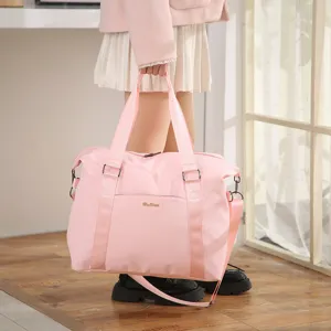 Large capacity pink travel bag being held by a model in a stylish indoor setting