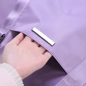 Close up detail of purple travel duffel bag showing smooth waterproof fabric and metal bar.