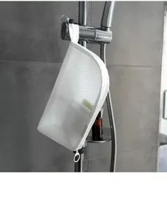 Detail shot of white mesh toiletry bag hanging in shower, convenient bathroom storage display.