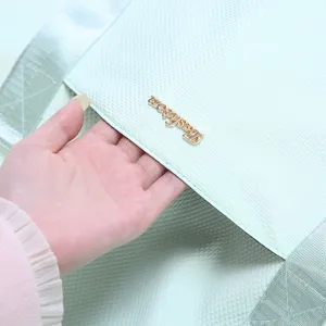 Close-up of a mint green waterproof travel bag showing the front pocket and logo detail