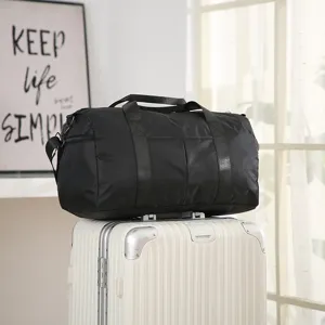 Detail view of black travel duffel bag on suitcase, showing durable handles and strap.