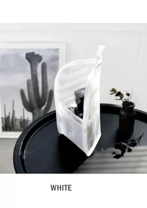 Detail view of white standing mesh travel cosmetic bag showing zipper and spacious inner capacity.