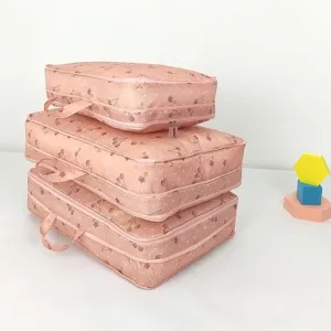 Vue détaillée du sac de voyage rose avec imprimé cerise présenté en pile soignée.