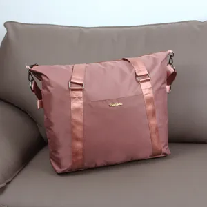 Waterproof travel duffel bag in dusty rose with sturdy handles, shoulder strap and metal detail.