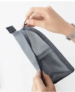 Detail view of grey mesh travel cosmetic bag interior opening and smooth zipper pull.