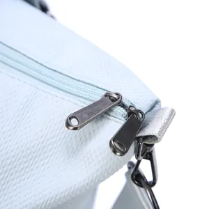 Close-up detail of double metal zippers on a light blue waterproof travel bag.