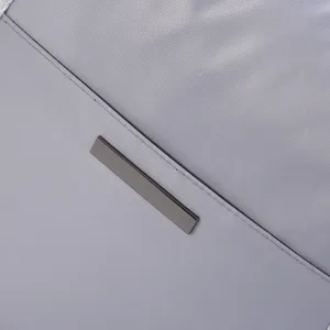 Grey travel bag detail shot featuring durable waterproof fabric and sleek metallic accent plate.