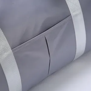 Grey travel gym bag detail view, durable fabric with external pocket and sturdy straps.