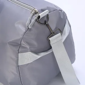 Close-up detailed view of grey travel duffel bag strap, metal hardware, and zipper closure.