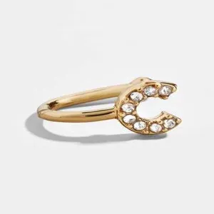 Λεπτομέρεια από χρυσό σκουλαρίκι ear cuff με το γράμμα C και λαμπερούς κρυστάλλους
