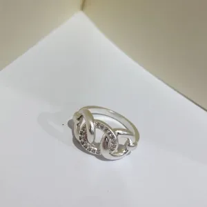 Elegante anello in ottone argentato con design a nodo e pavé di zirconi scintillanti