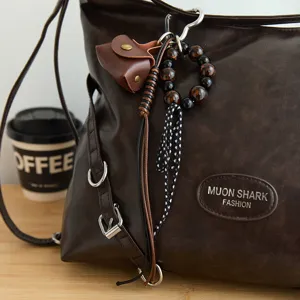 Detailweergave van retro lederen tassenhangers met mini-tasje en kralen op bruine tas