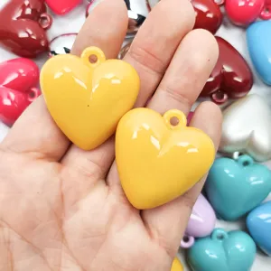 Close-up of bright yellow acrylic heart pendants with hanging holes for DIY jewelry