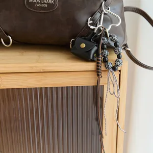 Detailweergave van een zwart vintage leren tasje en een hippe kralen tashaak voor tassen.