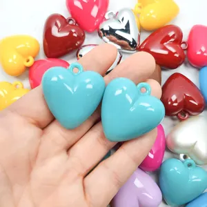 Macro detail of colorful gloss finish acrylic heart charms with hanging loops for DIY crafts.