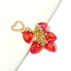 Close-up of translucent red strawberry charms on a gold-tone heart keychain
