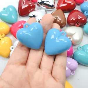 Colorful glossy acrylic heart charms held in hand for DIY jewelry making accessories