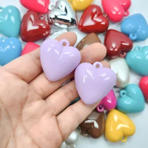 Hand holding two lavender glossy acrylic heart charms for DIY jewelry making