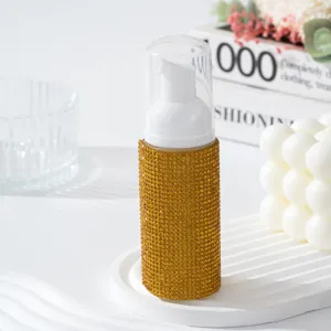 Détail d'un flacon pompe à mousse de luxe orné de strass dorés pour soins de voyage