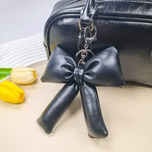 Détail d'un joli pendentif de sac et porte-clés en forme de nœud en cuir PU noir élégant.