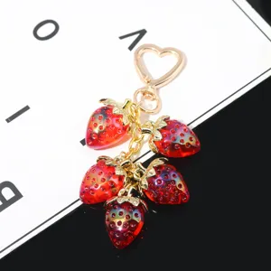 Detail view of sweet translucent red strawberry keychain with gold heart clasp.
