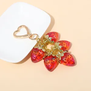 Detailed view of translucent red strawberry charms with gold heart-shaped clip