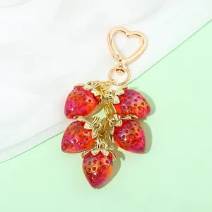 Detail of a sweet translucent strawberry keychain with heart clasp for bag decoration.