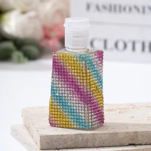 Macro view of rainbow rhinestone-covered perfume spray bottle on stone slab