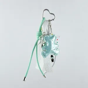Detailansicht eines mintgrünen Bären-Taschenanhängers mit glitzernden Bändern und Clip
