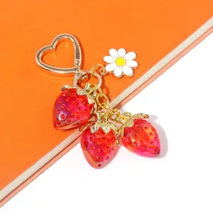 Close-up of sweet translucent red strawberry keychain with heart-shaped gold ring